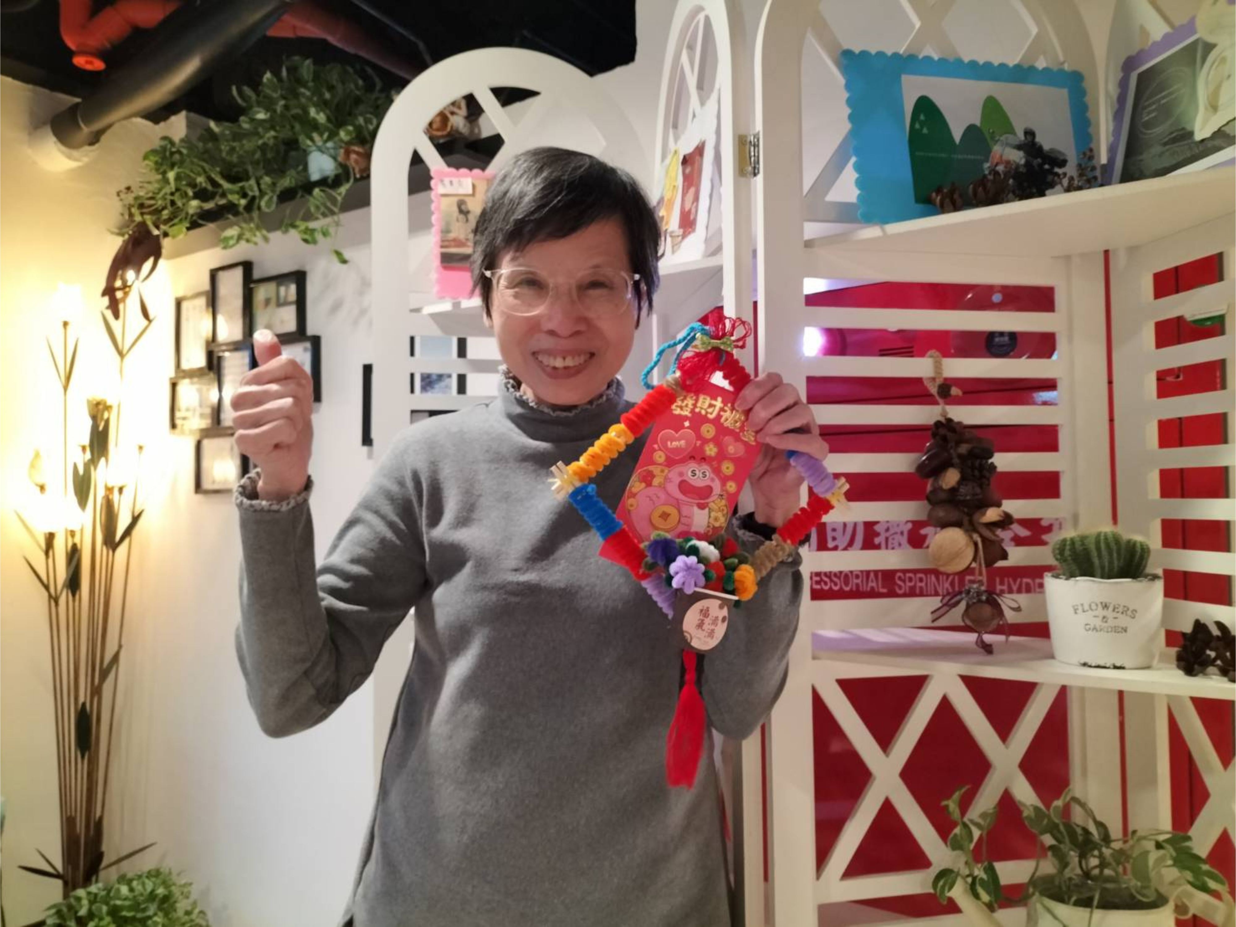 許金鷹拿著手作的春聯掛飾，笑容燦爛地比讚